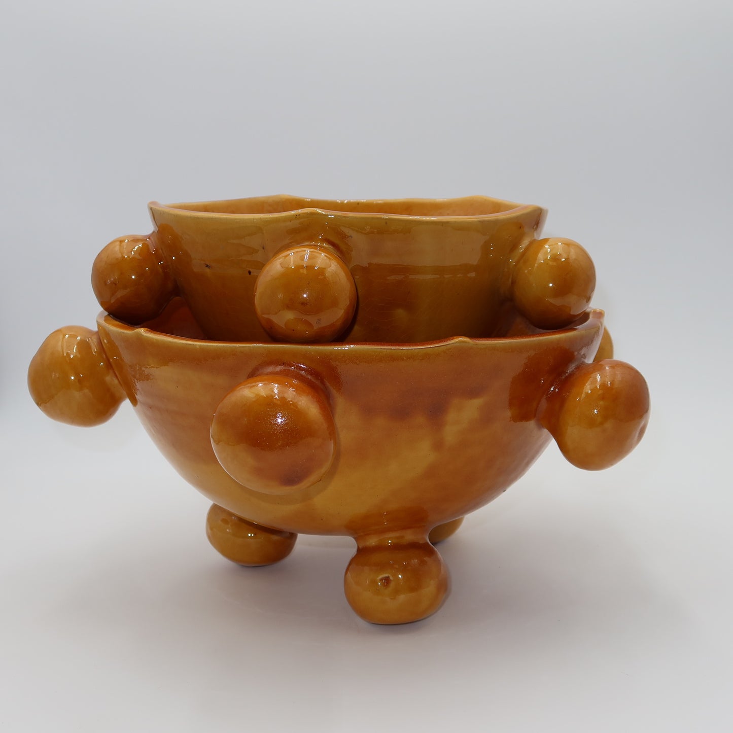 Ballo medium and large ceramic bowl, burnt yellow glaze, sculptural bobble details, ball feet, wavy rim
