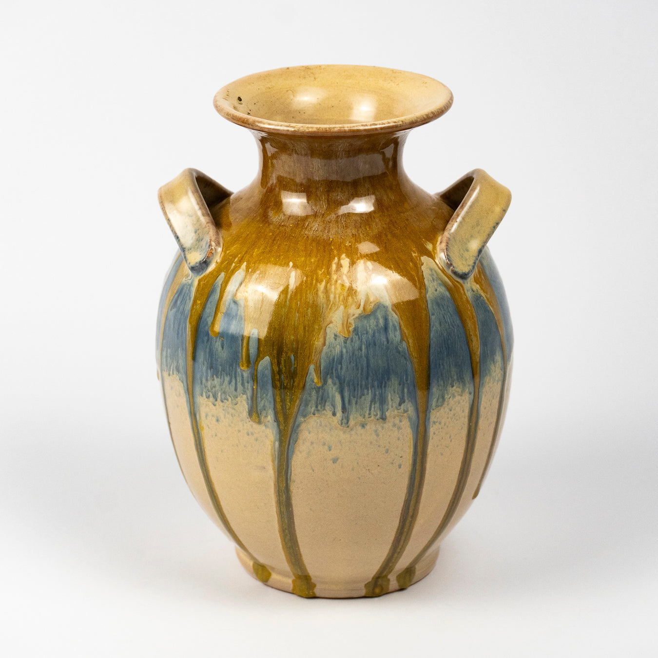 A ceramic vase with a glossy finish, featuring a two-tone glaze design with a warm brown and blue upper section and a beige lower section with brown drip patterns.