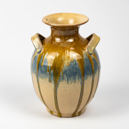 A ceramic vase with a glossy finish, featuring a two-tone glaze design with a warm brown and blue upper section and a beige lower section with brown drip patterns.