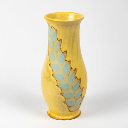 A yellow ceramic vase with a textured glaze and a vertical decorative pattern of light blue teardrop shapes outlined in brown, set against a plain white background.