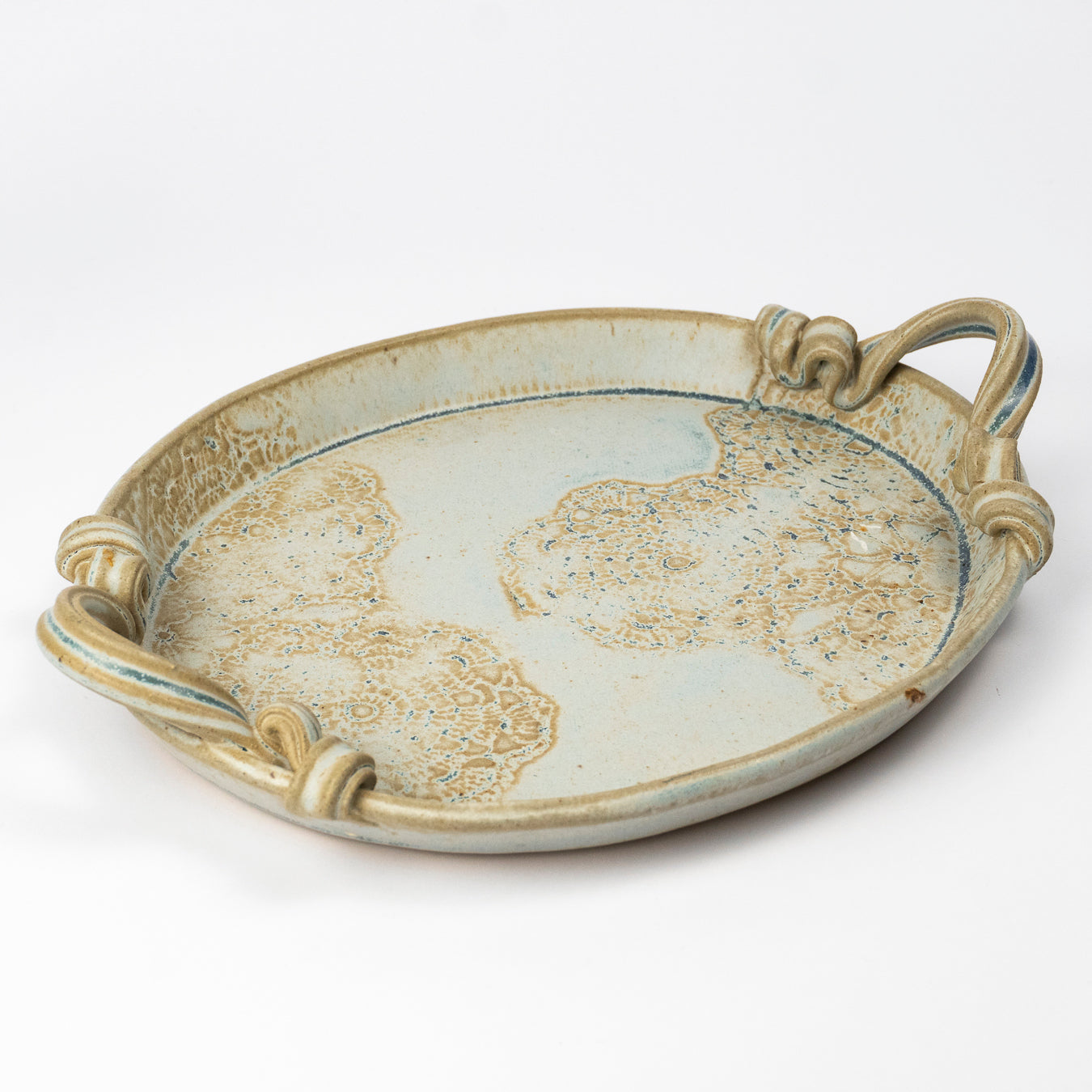 An oval ceramic serving tray with decorative handles, featuring a light blue-gray glaze with gold and beige marbled patterns, photographed on a white background.