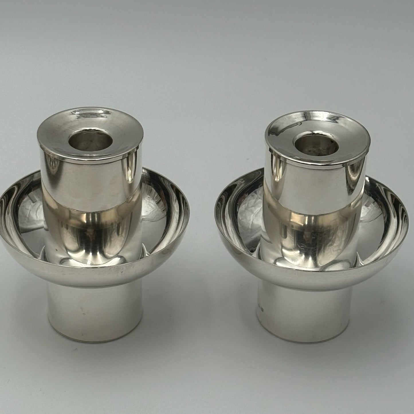 Two metallic candle holders on a gray background