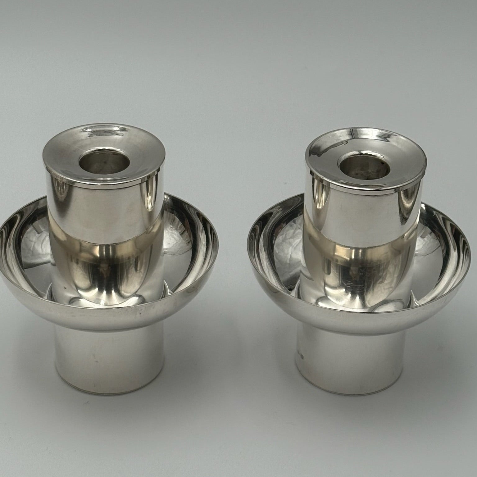 Two metallic candle holders on a gray background