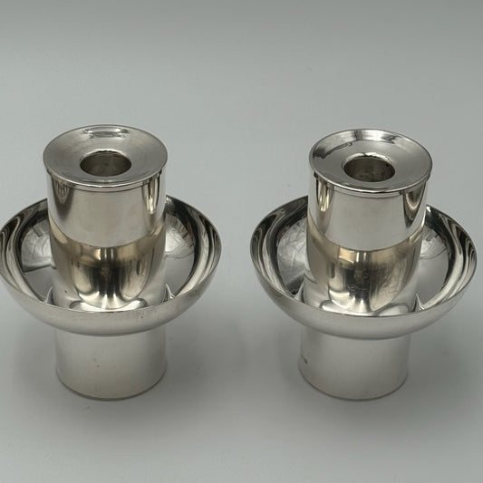 Two metallic candle holders on a gray background