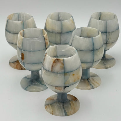 Set of six marbled stone goblets on a white background