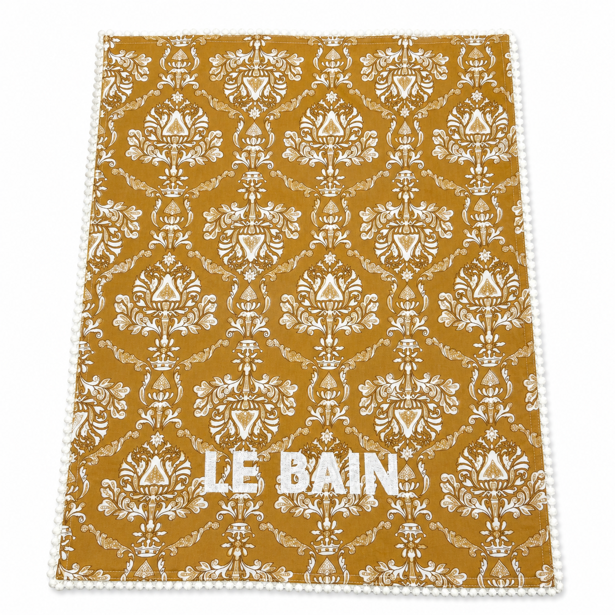Close up of Alma Le Bain golden ochre damask block-print guest towels, white LE BAIN embroidery, pom-pom trim, terry lined, set of two