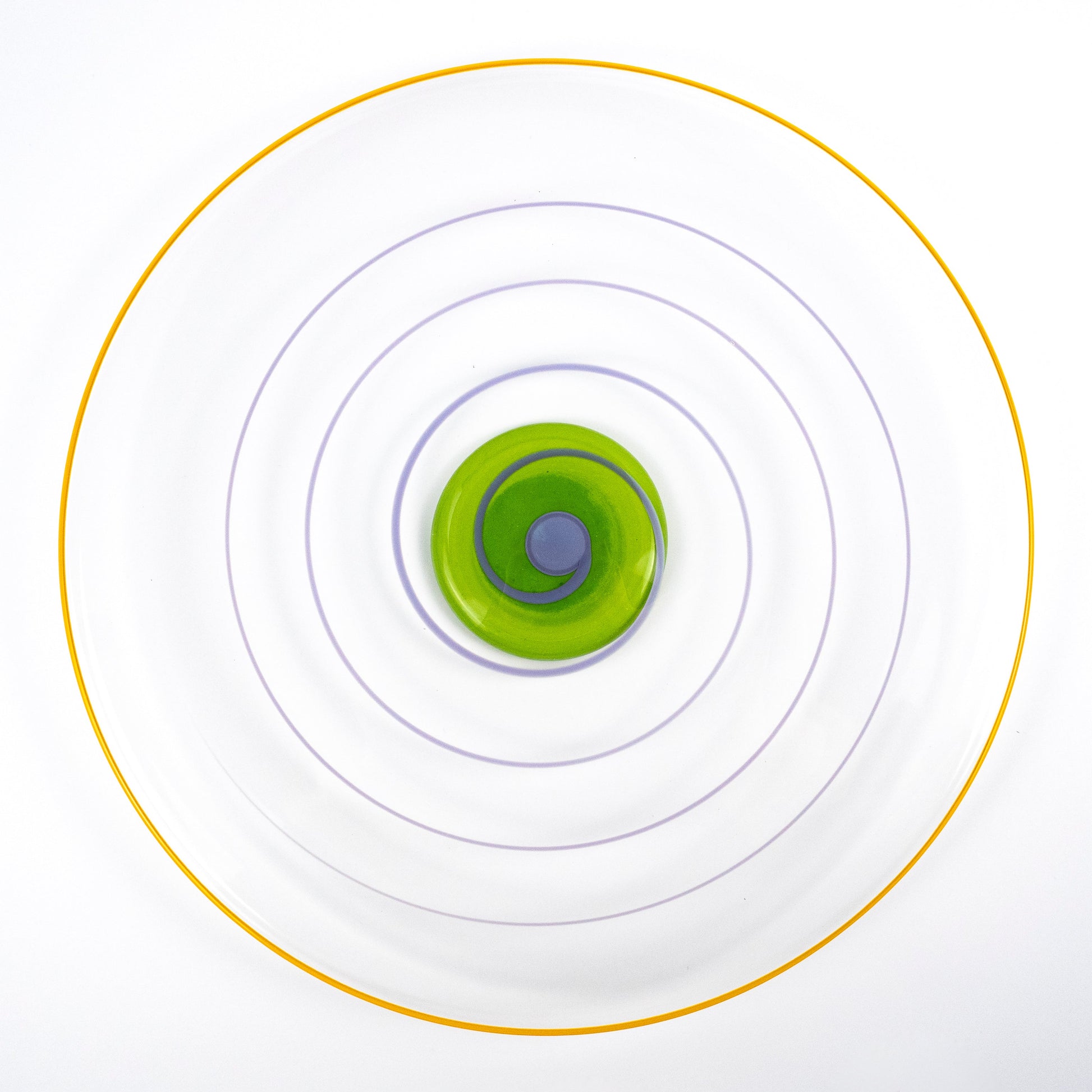 A top-down view of a clear circular plate with concentric rings in yellow, purple, and green, centered on a white background.