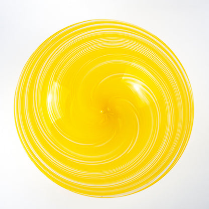 A bright yellow glass bowl with a spiral pattern of concentric rings, photographed from directly above on a white background.