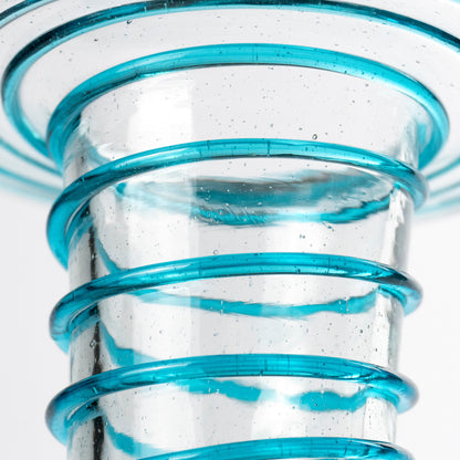 Close-up of a clear glass vessel with a flared rim and multiple horizontal bands of translucent bright blue glass around the body, shown on a white background.