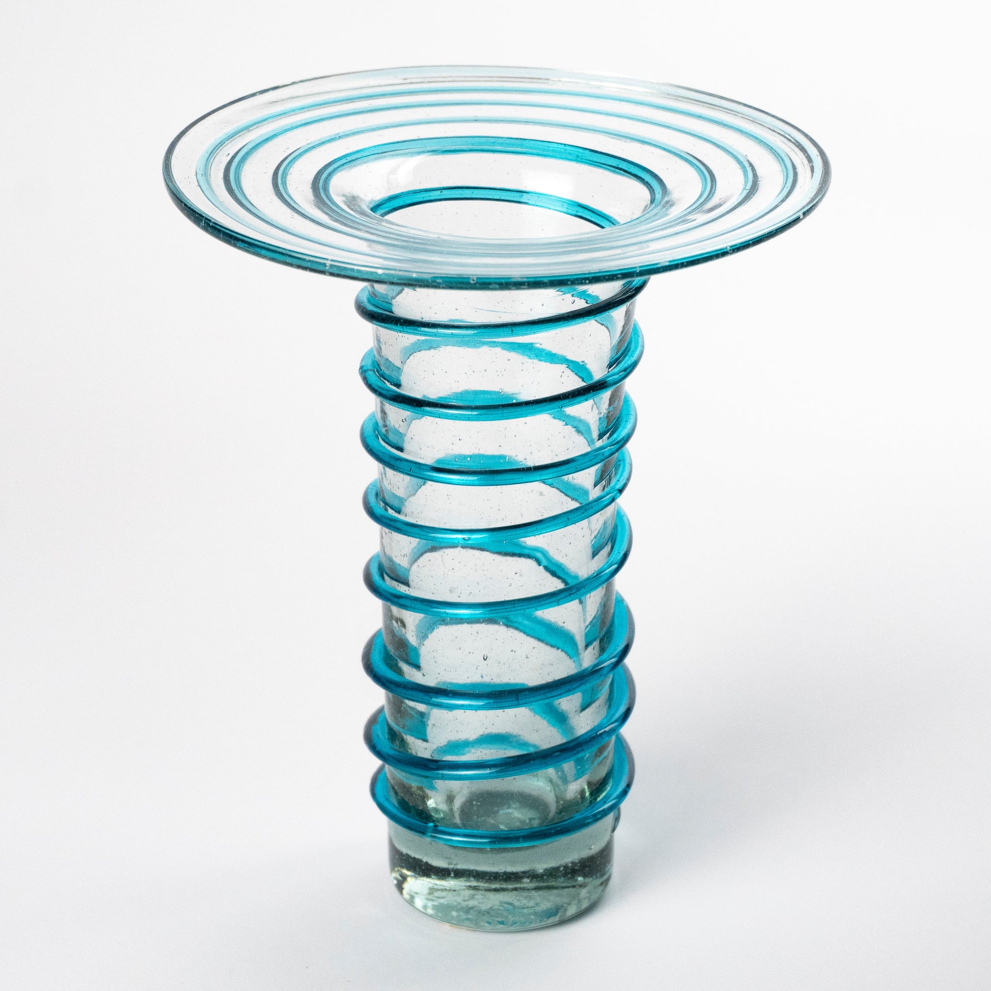 A clear glass table vase with a wide, shallow round top and a fluted stem, accented by vibrant turquoise blue concentric rings, shown on a white background.