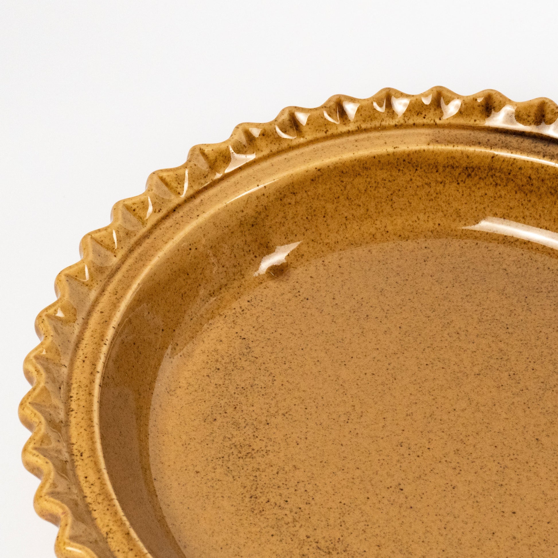 Close-up of a round ceramic plate with a scalloped rim, shown on a plain white background.