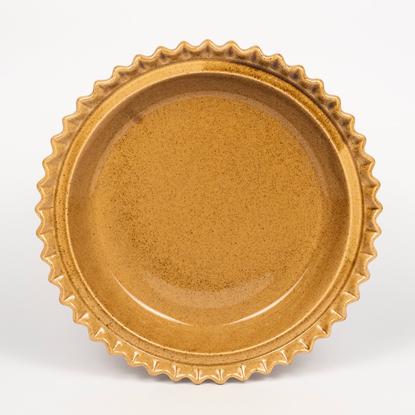 A round ceramic plate with a scalloped, wavy rim, shown from a top-down view on a clean white background.