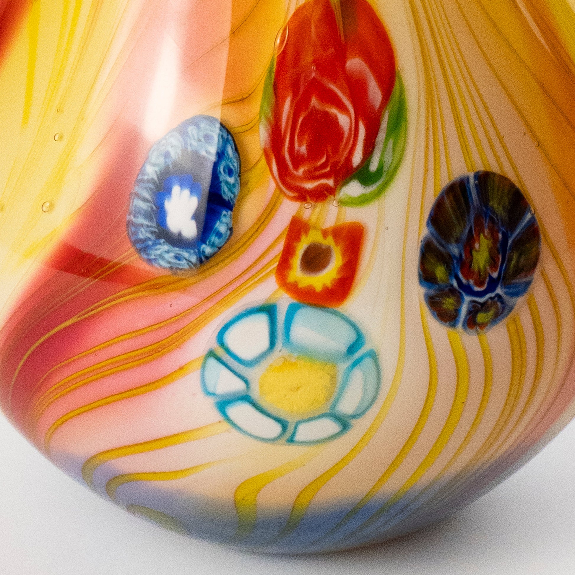 Close-up of a colorful glass vase featuring yellow, orange, pink, and white marbled swirls with hand-painted floral motifs in red, blue, and light blue.