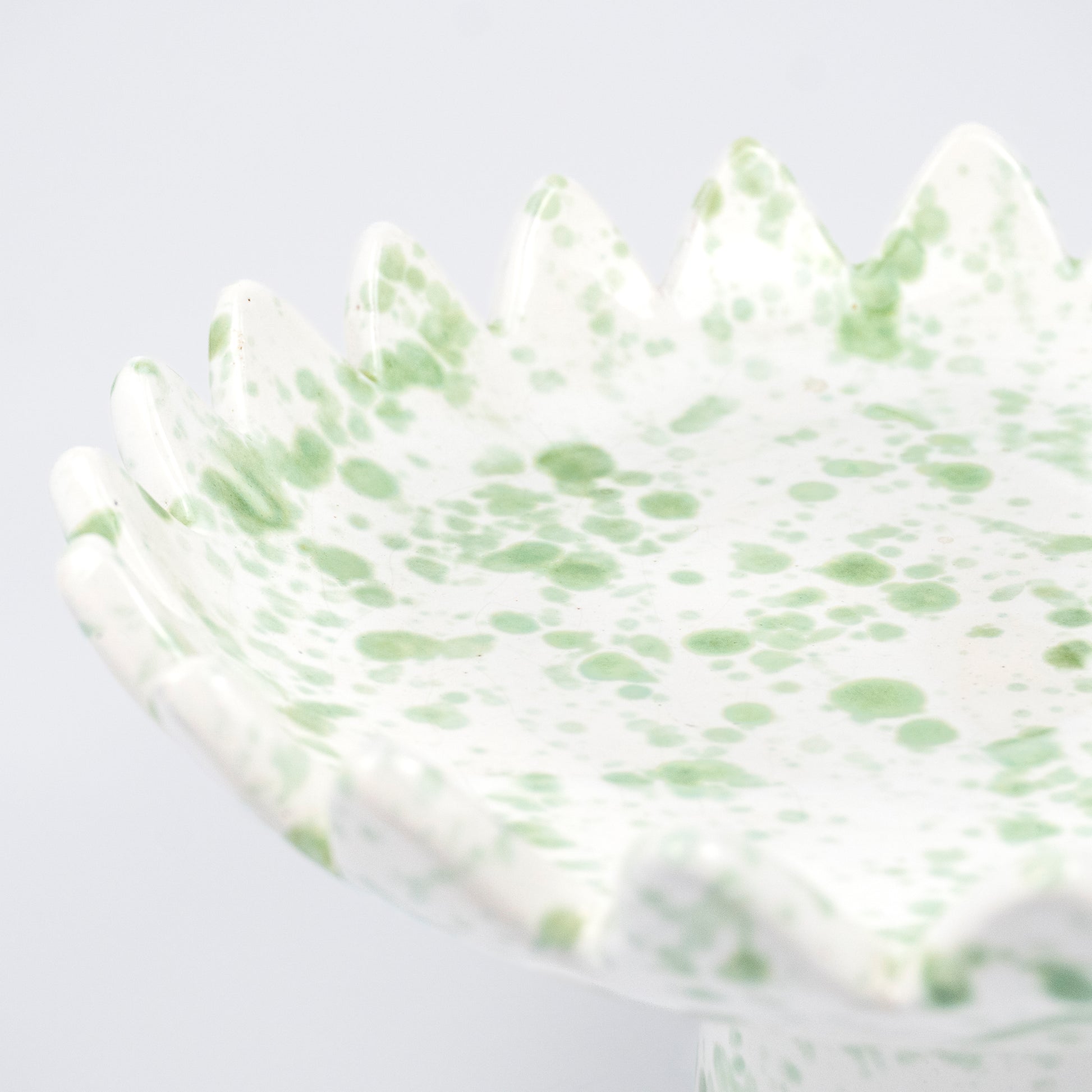 Floree ceramic pedestal bowl, white with light green speckle glaze, sawtooth zigzag rim, footed base