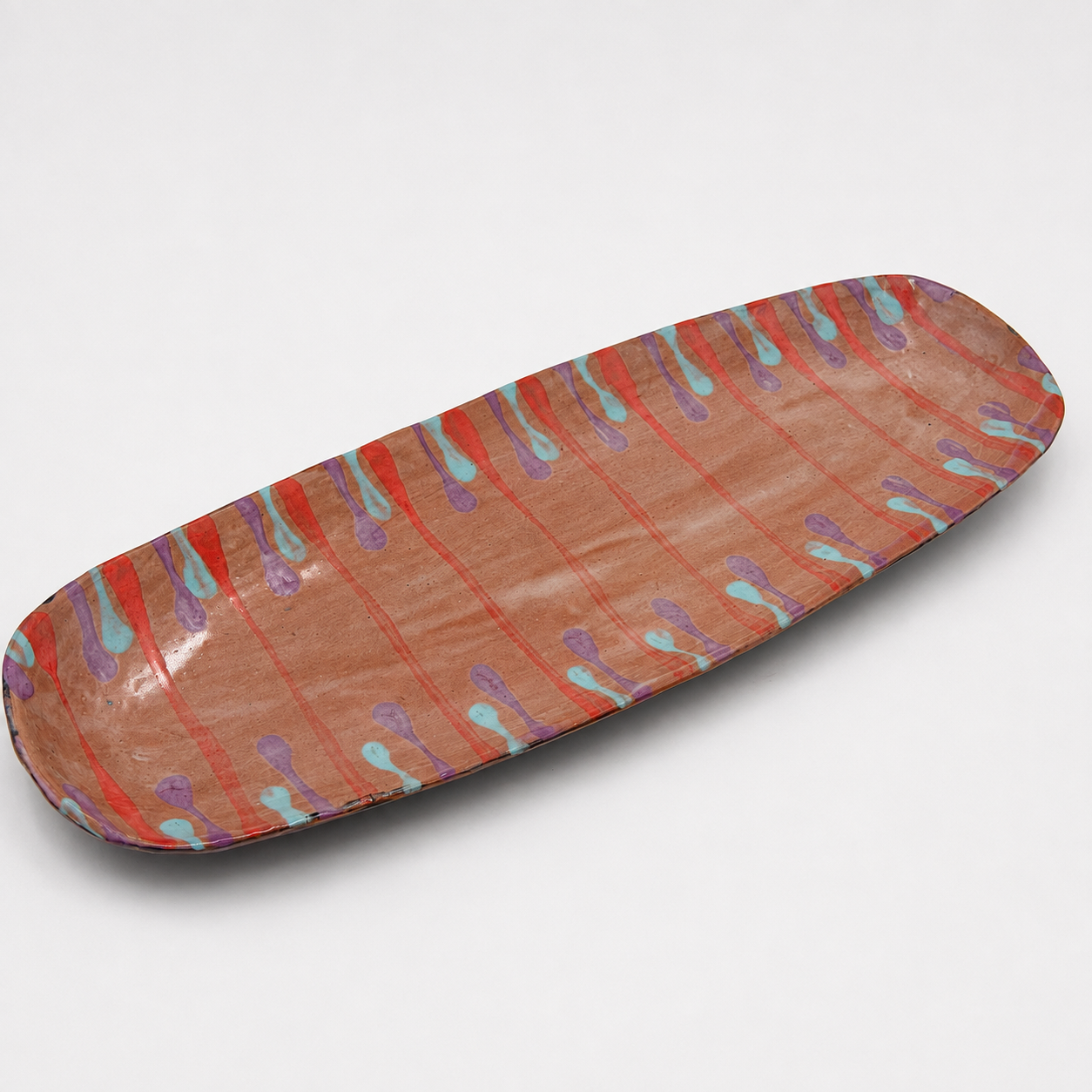 Lonza oven-safe ceramic serving platter, long narrow shape in terracotta with hand-painted coral, purple, and turquoise drip pattern