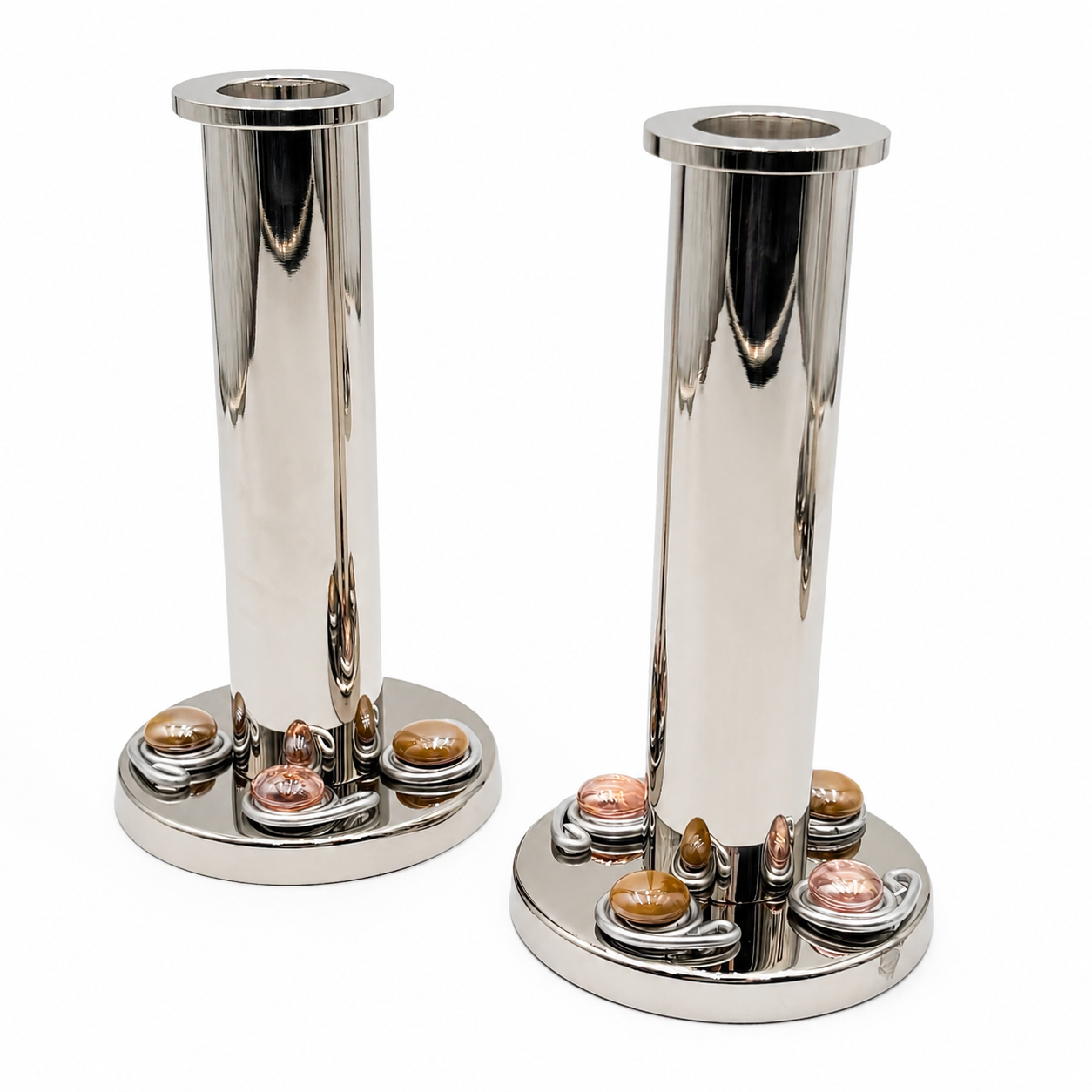 Two polished silver metal candlesticks with circular bases featuring small amber and rose gold gems, shown on a white background.
