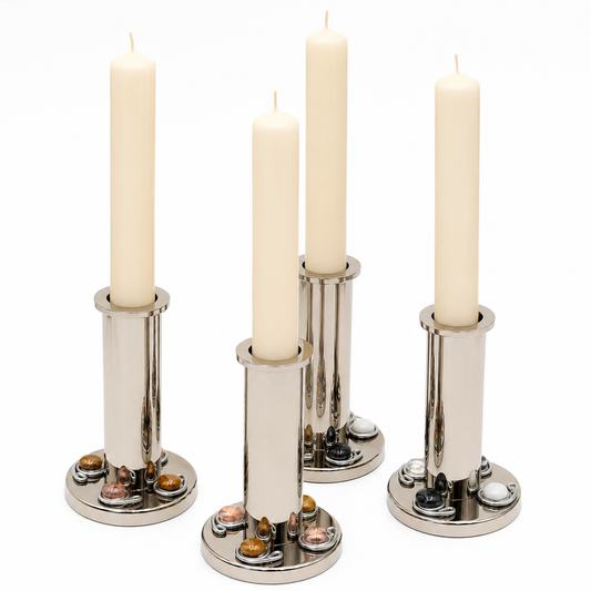 Four silver metal candlesticks holding white taper candles, arranged on a plain white background.