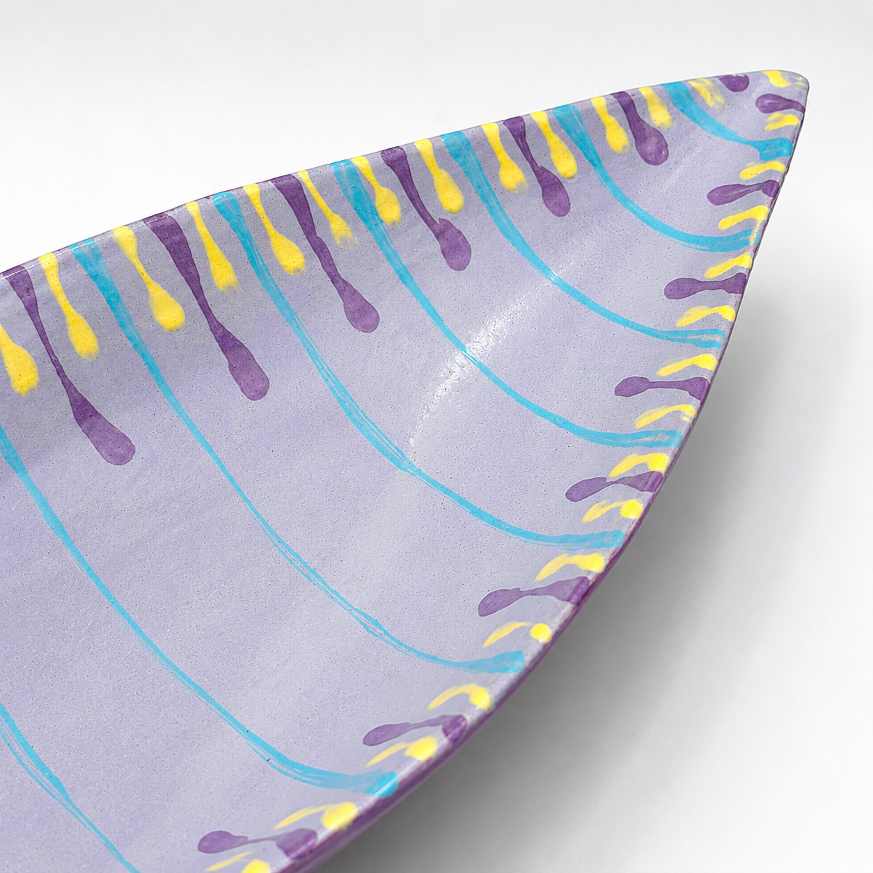 Detail view of Santino oven-safe ceramic serving bowl showing colorful drip glaze pattern and pointed edge