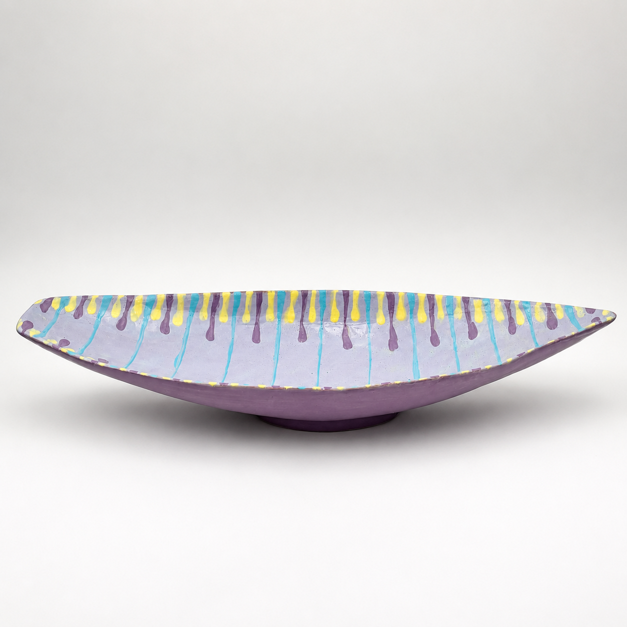 Side view of Santino oven-safe ceramic serving bowl showing elongated boat shape and purple glaze exterior