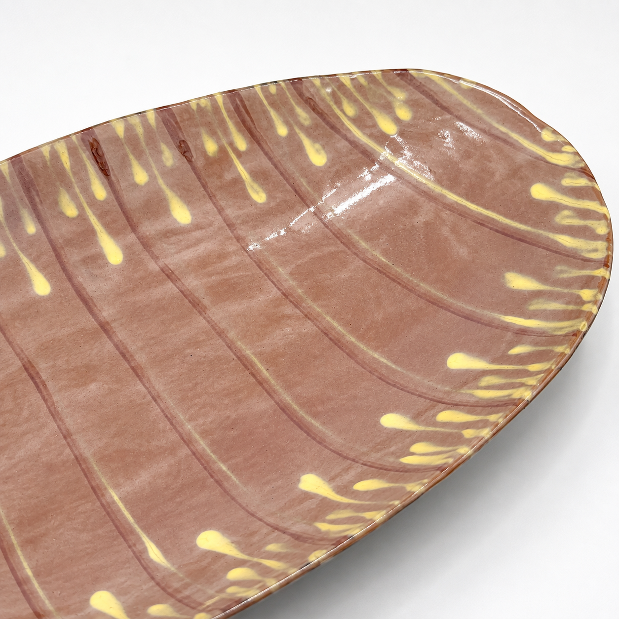 Detail view of Taro oven-safe ceramic serving bowl showing yellow and burgundy drip glaze pattern