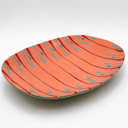 Tiera oven-safe ceramic serving bowl in coral with hand-painted magenta, teal, and blue drip pattern