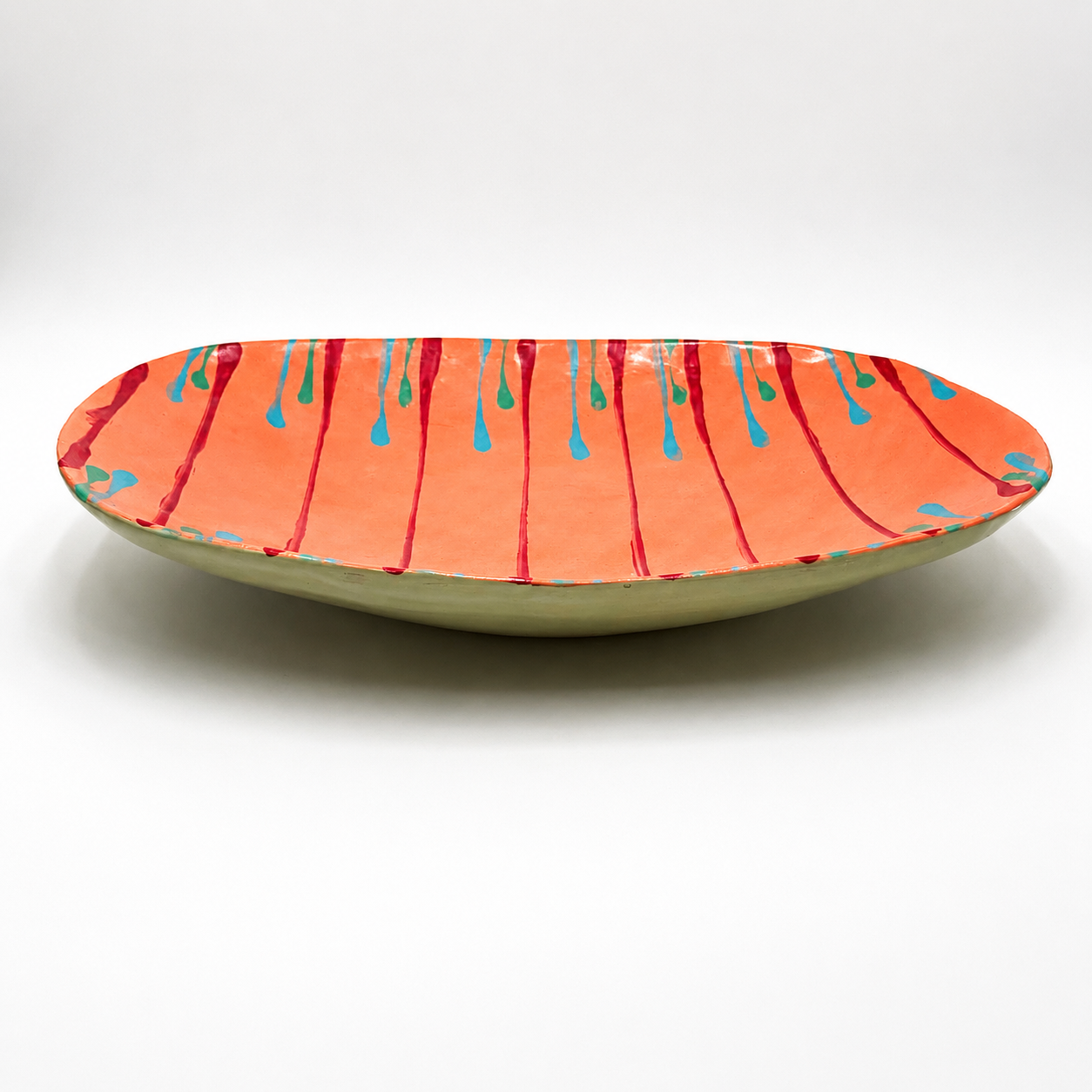 Side view of Tiera oven-safe ceramic serving bowl showing shallow profile and coral glaze exterior